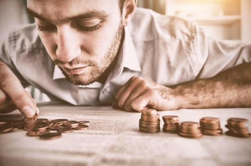 man counting coins and stacking them up